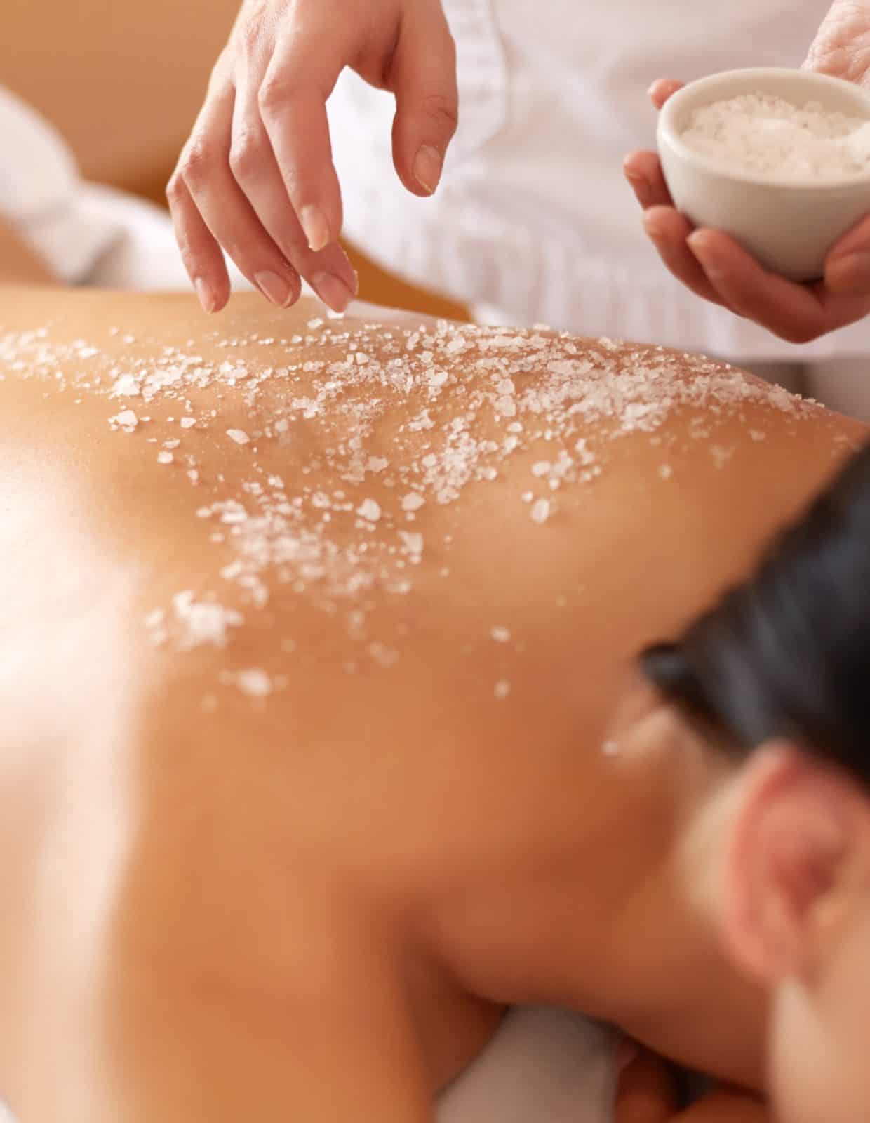 A person receiving a salt scrub treatment on their back